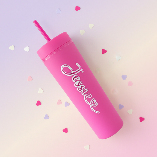 Personalised hot pink cold cup with custom name, handmade in UK, lying flat on dreamy pastel gradient background with scattered heart confetti